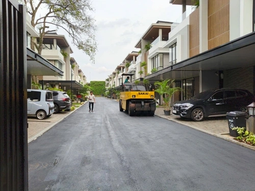 Proses pemadatan aspal menggunakan tandem roller di Serang